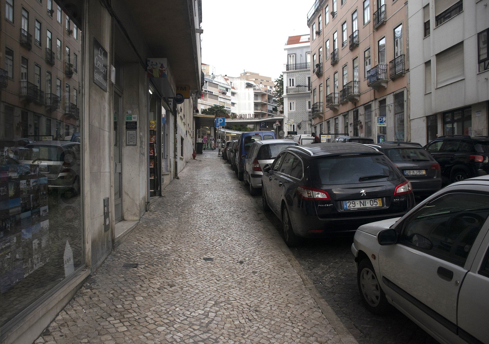 A street in Lisbon, Portugal. In one of the shop windows there is an exhibition of Shutter Hubs Postcards from Great Britain project, lots of postcard sized photographs