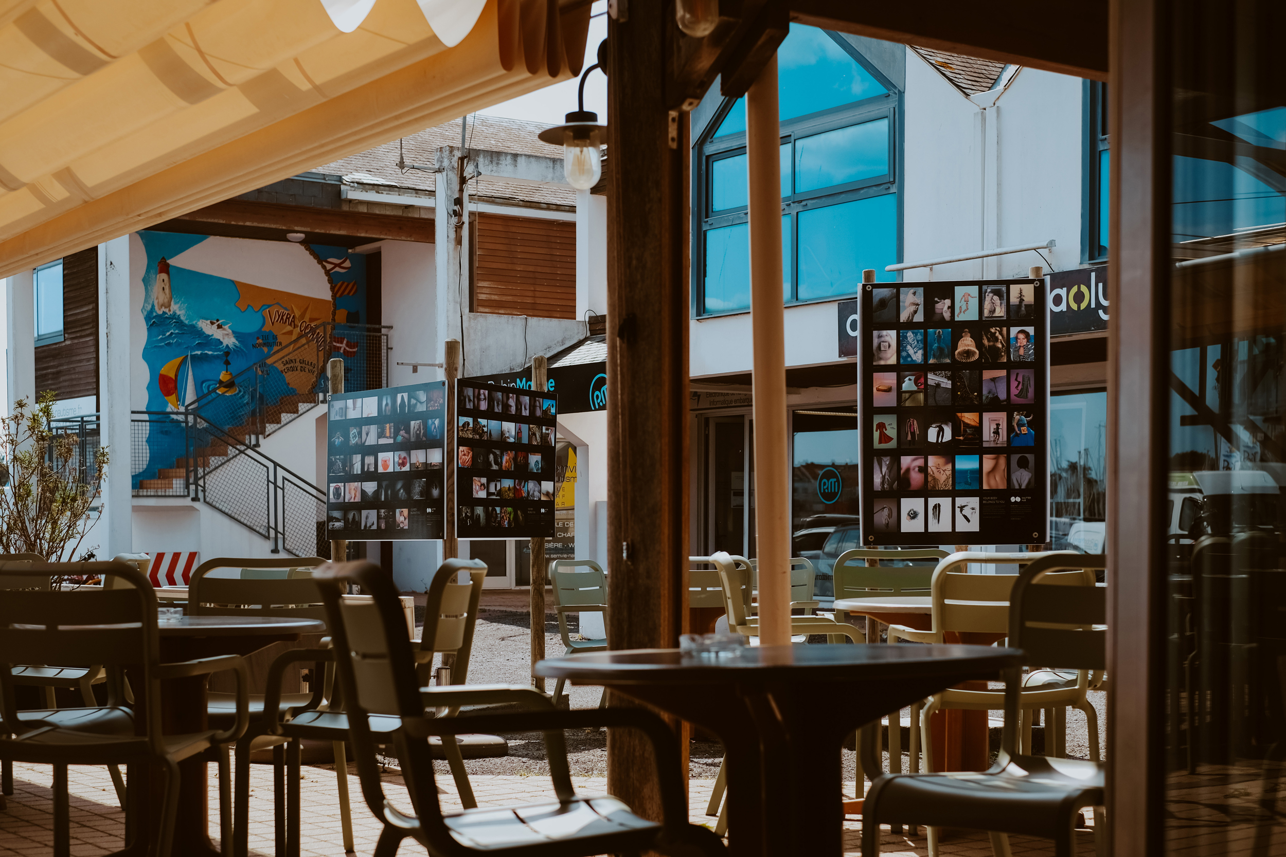 a photograph looking out of a cafe towards a outdoor space where exhibition panel boards display photographs