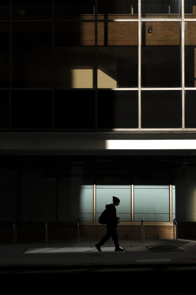 Silhouette of a person walking under a partially lit building.