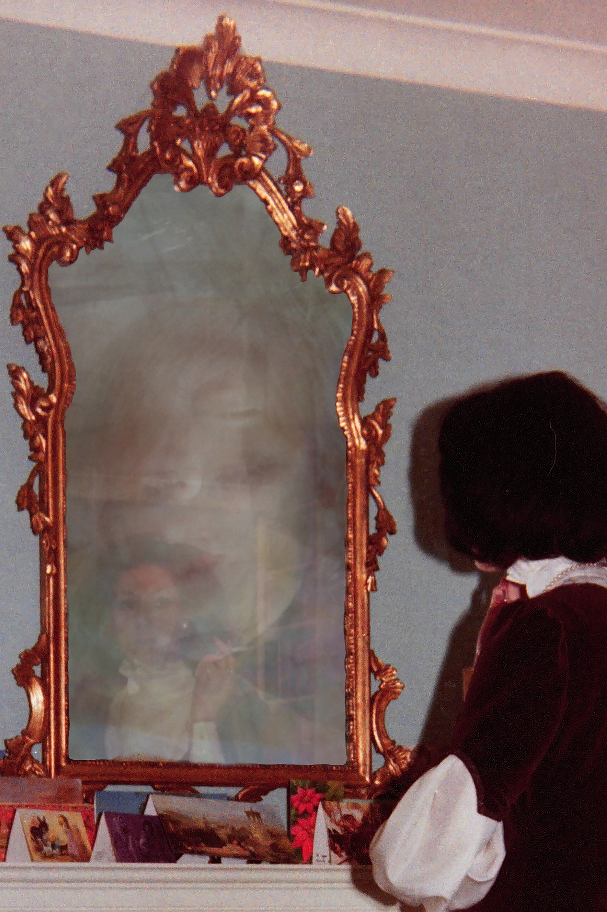 A woman looking at her reflection in a mirror and a layered image of a child looks back.