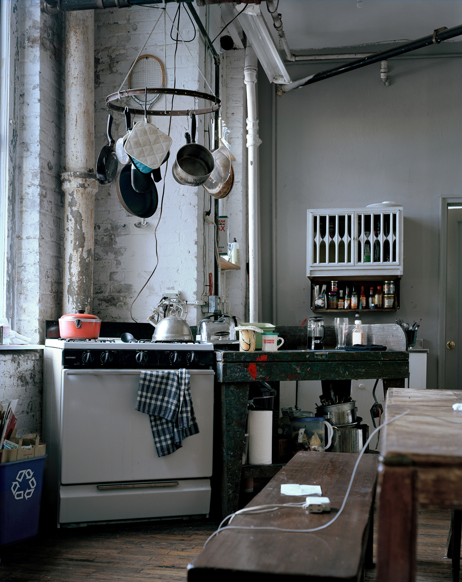 A kitchen with pans and pots hanging from a repurposed bike wheel suspended from the ceiling